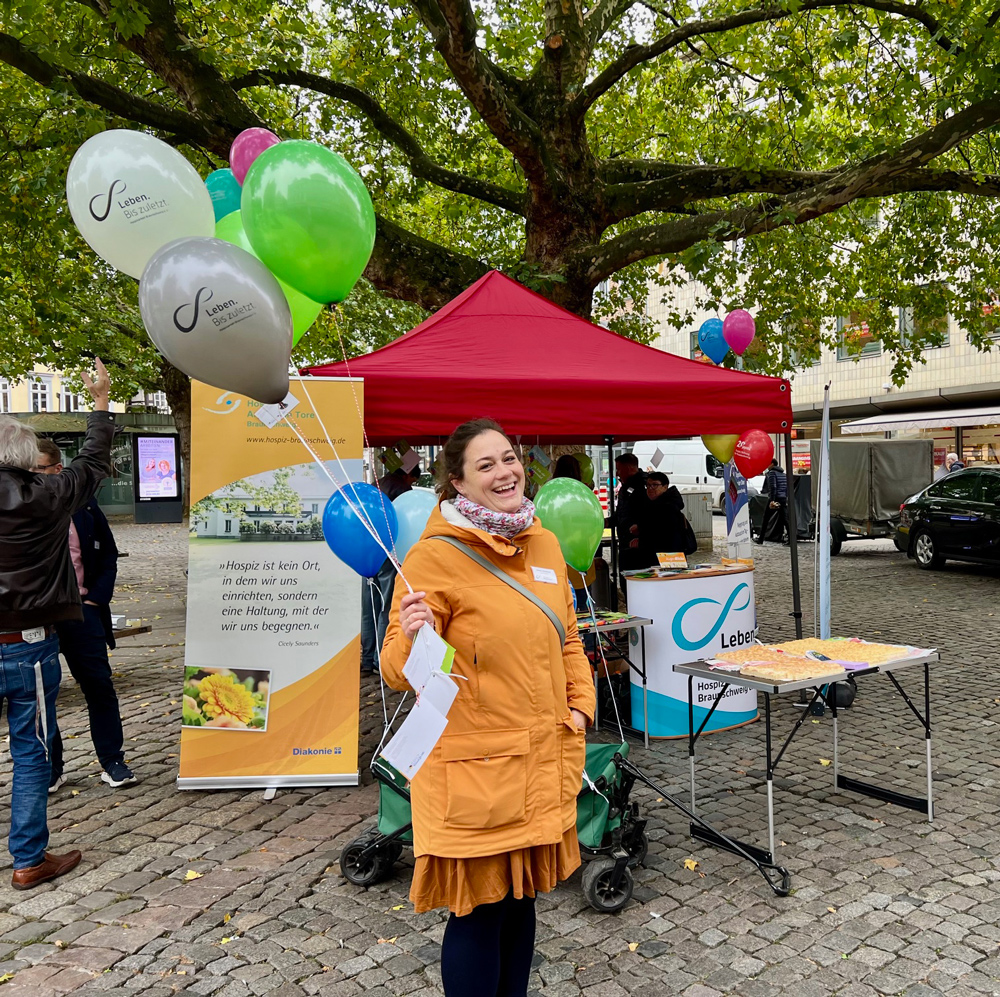 Lachende Frau mit Luftballons in der Hand auf dem Stand vor dem Kohlmarkt in Braunschweig